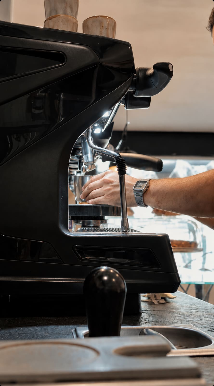 Barista extrayendo espresso en la máquina negra de la barra de Cacto