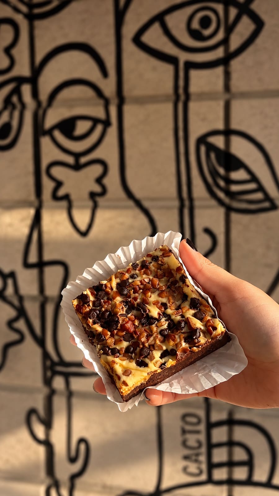 Brownie con nuez y chispas de chocolate frente al mural de Cacto